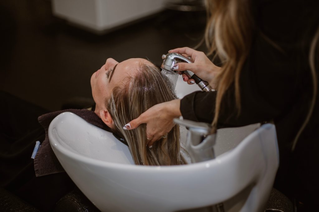 Einer Frau werden in einem Friseursalon die Haare gewaschen.