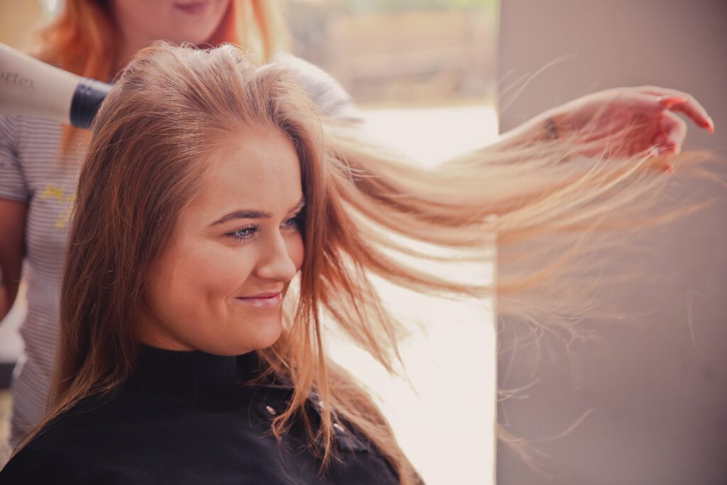 Eine Friseurin föhnt einer Kundin die Haare