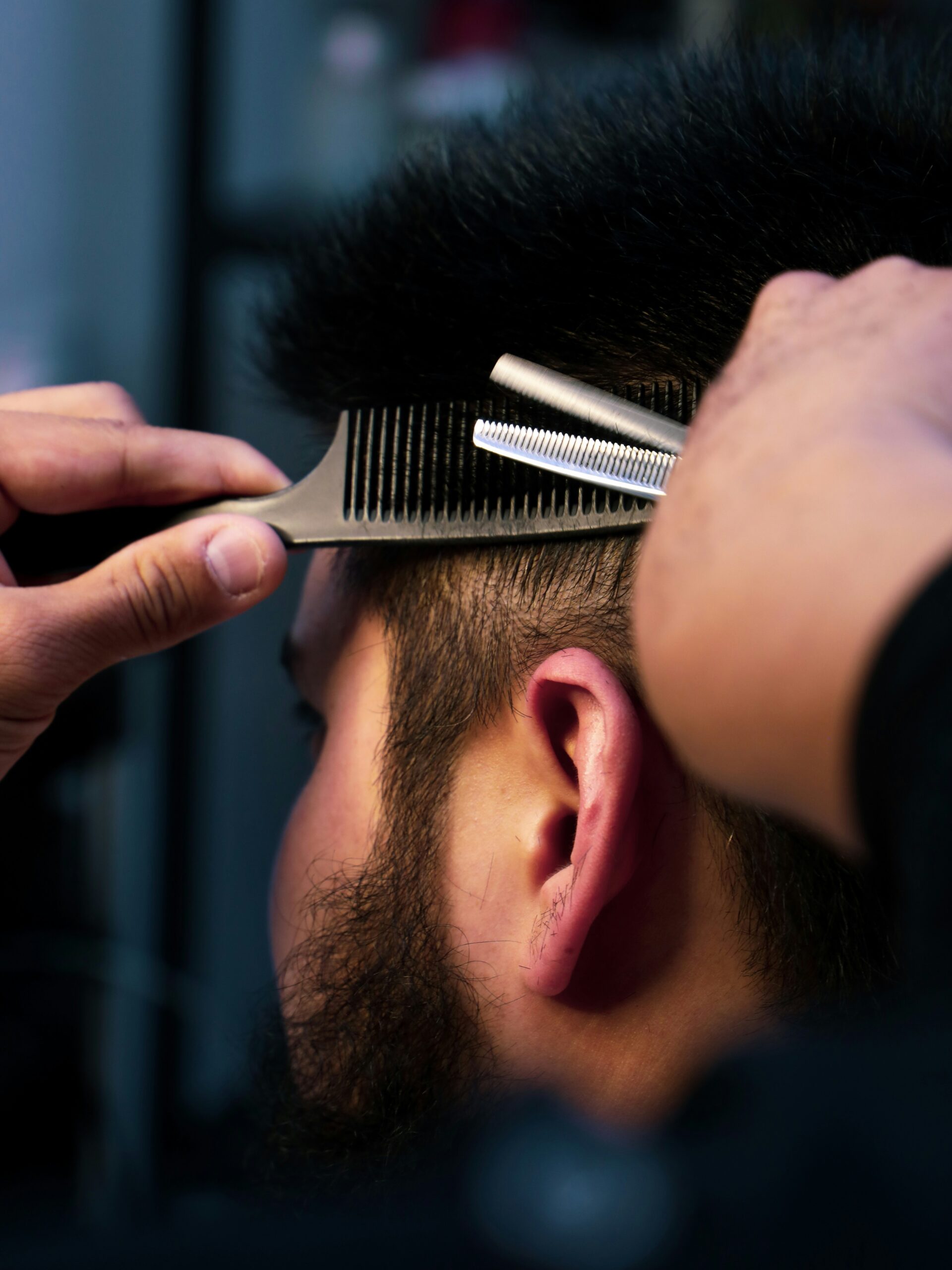 Nahaufnahme eines Barbers, der einem Kunden einen Vokuhila schneidet und sorgfältig die Seiten formt.
