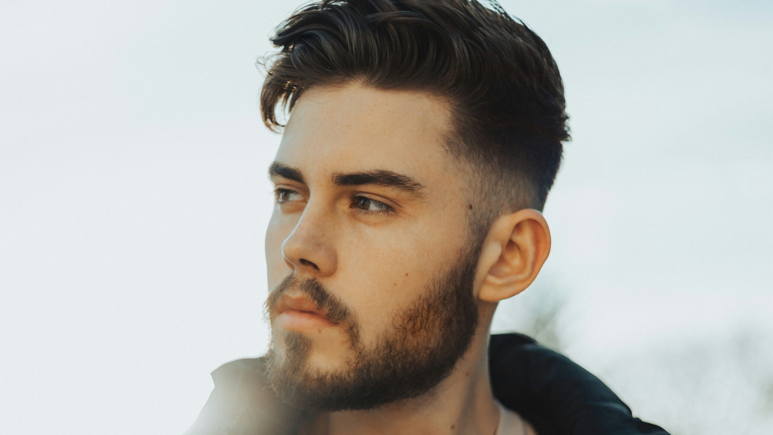 Mann im Freien mit dunklem Haar und einem Taper Fade Haarschnitt mit texturiertem Deckhaar