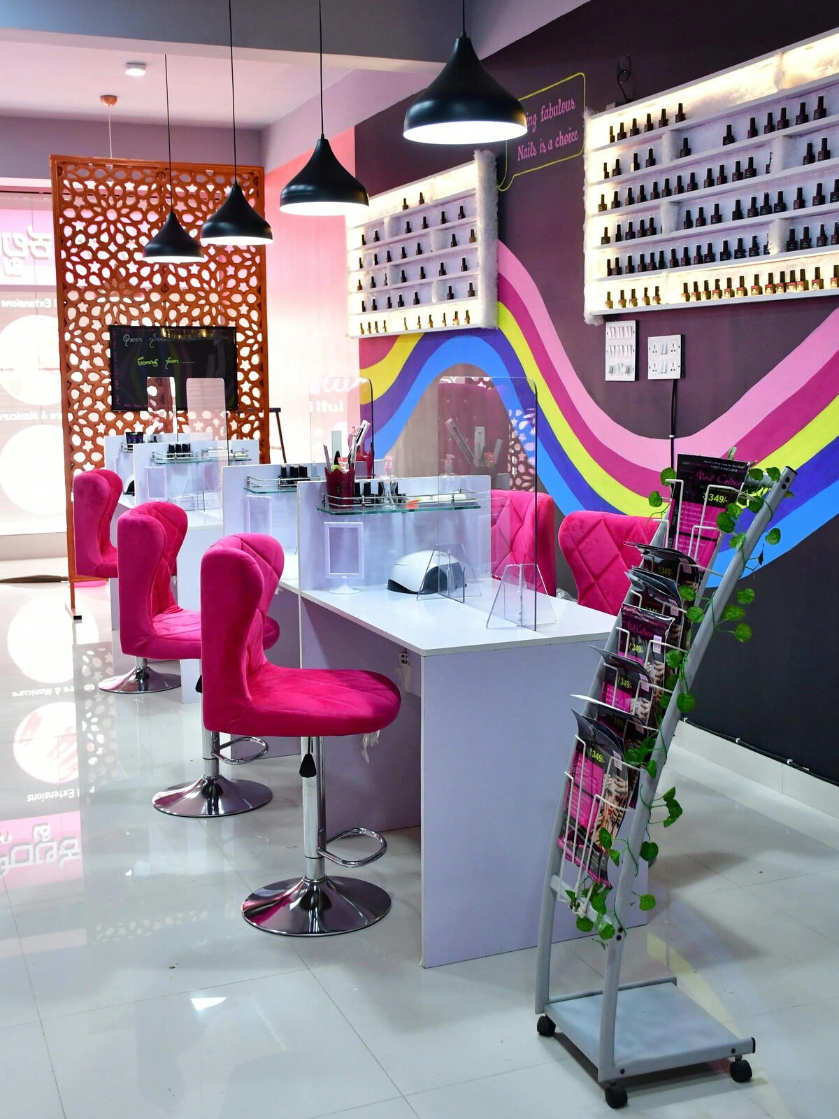 Innenraum eines Nagelstudios mit sauberen weißen Tischen, rosa Samtstühlen und einer violetten Wand