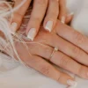 Klassische weiße French-Tip-Maniküre auf naturbelassenen, eckig gefeilten Nägeln auf weißem Stoff