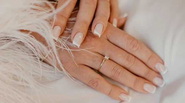 Klassische weiße French-Tip-Maniküre auf naturbelassenen, eckig gefeilten Nägeln auf weißem Stoff