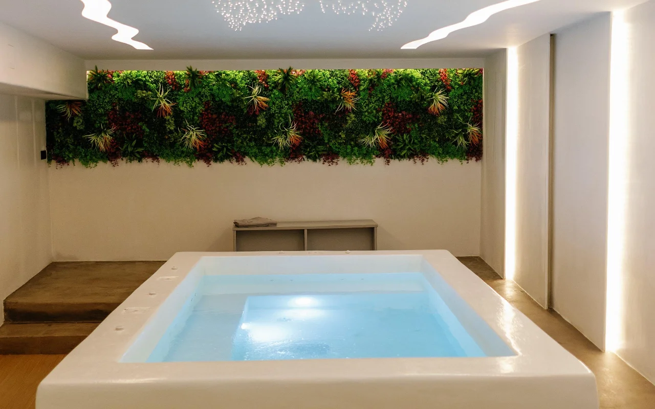 Das Hydrotherapiebecken von Liana Spa Therapy auf Naxos, sanft von innen beleuchtet, unter einer bunten begrünten Wand aus konservierten Pflanzen und einer Decke voller winziger Sternenlichter.