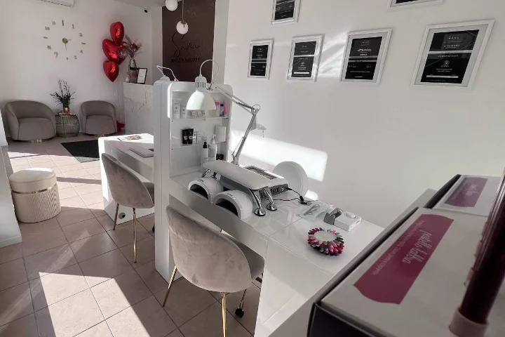 Weißes Nagelstudio Sara Nails&Beauty in Tortolì mit grauen Samtstühlen und gerahmten Zertifikaten an der Wand.