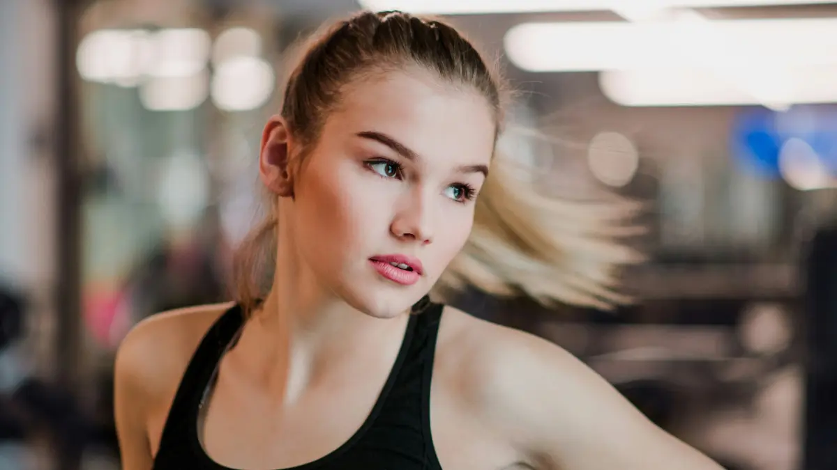 Eine junge Frau im Sporttop bewegt sich zur Seite, während ihr Pferdeschwanz nach außen schwingt