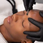 Nahaufnahme einer Kosmetikerin, die bei einer Kundin im Salon ein Dermaplaning durchführt